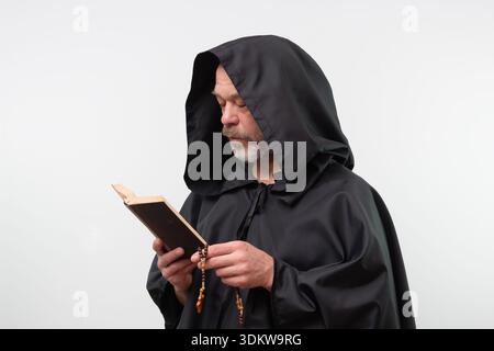 Bearded monk with hood reading religious book on white background Stock Photo