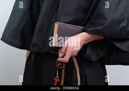 Close up of monk hands holding book and rosary isolated Stock Photo