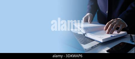 Close-up of a businessman writing notes in a daily planner at a bright workspace, focused on business planning and organization. Stock Photo