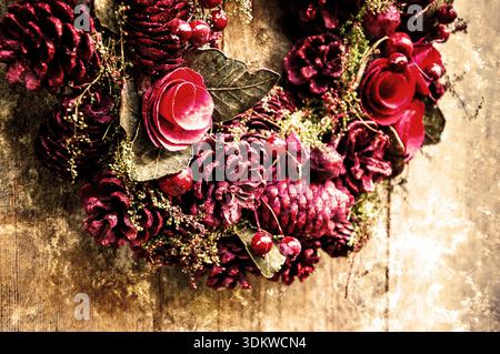 Vintage Christmas wreath with cinnamon sticks, dry oranges, red balls and stars on the grungy wooden door. Greeting card. Retro aged photo with scratc Stock Photo