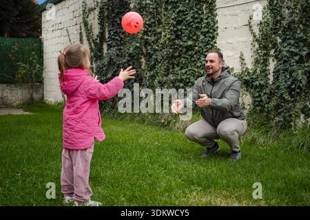 Father daughter playing catch with ball in backyard Stock Photo