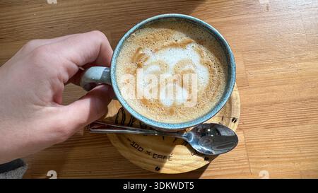 Top view of cappuccino coffee with bear latte art held by hand Stock Photo