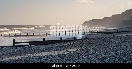 Waves rolling in during the morning sunshine on a hazy winter day Stock Photo