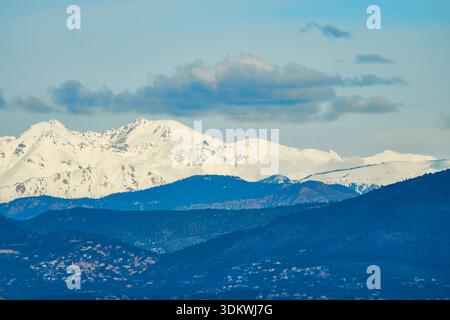 Snow-Capped Mountain Range Under Clear Blue Sky With Clouds and Rolling Foregrounds Stock Photo
