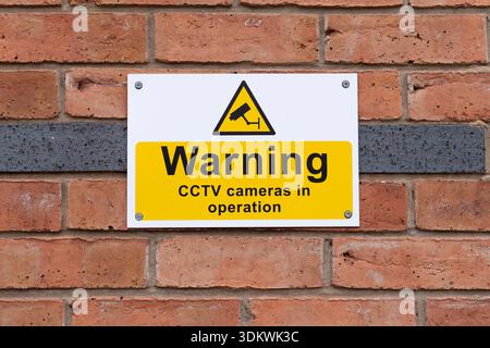 Close up isolated sign in outdoor position on brick wall advising the UK public: CCTV cameras are in operation in this area. Stock Photo