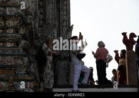 BANGKOK, THAILAND-JAN 15, 2026: Tourists tourist taking a photograph with smartphone and exploring at Thai temple, low angle view, at Wat Aru Stock Photo