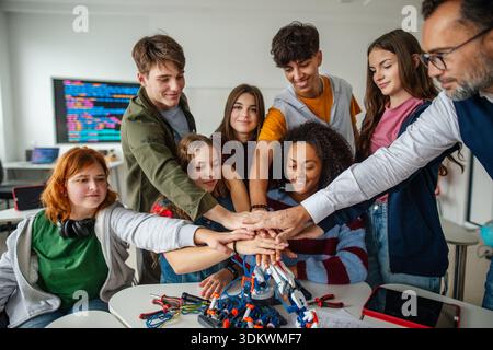 Diverse high school team celebrating teamwork during robotics project ...