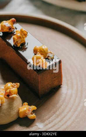 A dessert with a brown base and yellow popcorn on top. The plate is brown and the dessert is placed on top of it Stock Photo