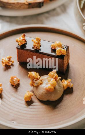 A dessert with a brown crust and a layer of caramel on top. The dessert is topped with popcorn and has a creamy white sauce Stock Photo