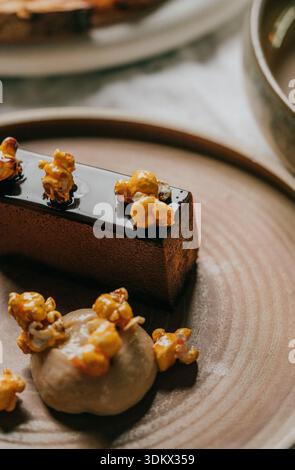 A dessert with a brown crust and a layer of caramel on top. The dessert is topped with popcorn and is served on a brown plate Stock Photo