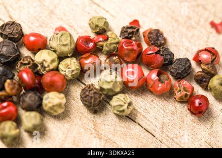 A bunch of different colored peppers are scattered on a wooden surface. The peppers are of various sizes and colors, including red, green, and yellow. Stock Photo