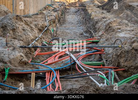 Underground Utility Cables at Construction Site, Multiple Electrical and Communication Lines Laid in Soil Ready for Backfilling Stock Photo