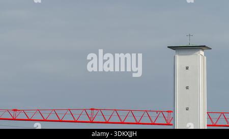 White Church Tower and Red Crane Against Gray Sky Stock Photo