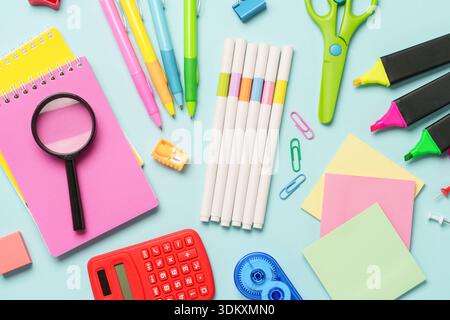 Office stationery on blue background. Top view. Notepad, markers, pens, calculator and others. Stock Photo