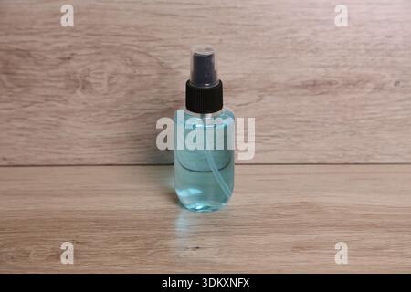 A small bottle filled with blue liquid stands upright on a wooden surface. The design is basic and clear, emphasizing the contents of the bottle. Stock Photo