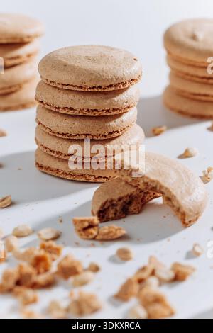Stacked peanut macarons with bitten cookie and crumbs on white background Stock Photo