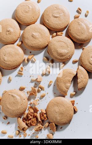 Peanut macaron cookies with crumbs and nuts on white, top view, hard light Stock Photo