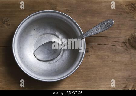 Empty aluminum bowl with spoon on the old wooden table Stock Photo