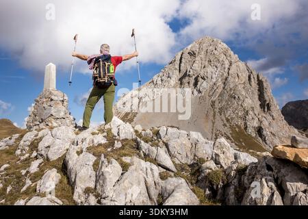 Hiker cheering elated and blissful with arms raised in the sky after hiking to mountain top summit above the clouds. Success concept Stock Photo