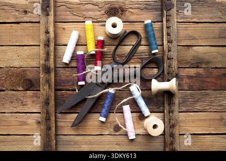 Vintage Background with sewing tools/Sewing kit. Scissors, bobbins with thread on the old wooden background Stock Photo