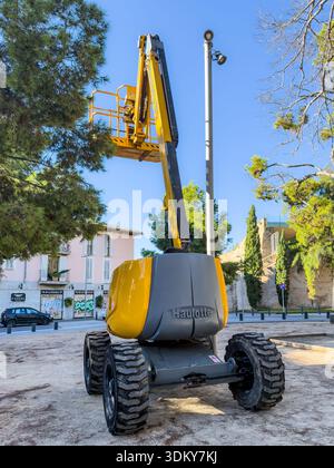 A construction lift positioned on a site, ready to elevate workers for maintenance or construction tasks in an urban area Stock Photo