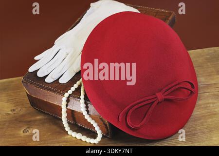 Red hat, white gloves and bone beads on leather case Stock Photo