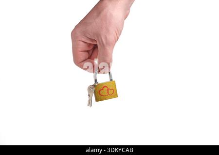 Man hand holds small golden lock with two red hearts and keys on light background Stock Photo