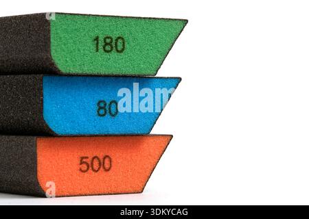 Three abrasive sponges different grain sizes 180, 80, 500, stacked vertically. White background, emphasis on color coding and shape Stock Photo