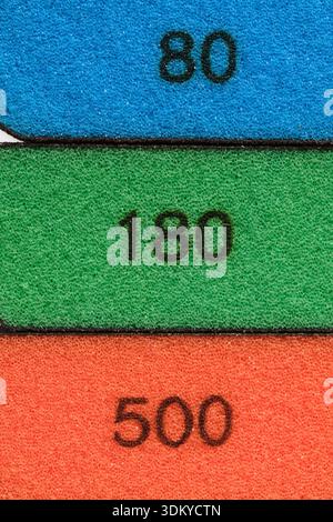 Abstract macro image three abrasive sponges blue, green, orange with clearly visible numbers grain size 80, 180 and 500 Stock Photo