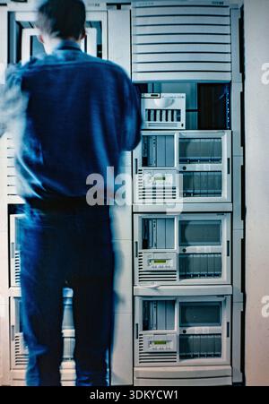 Person working in a data center with Hewlett-Packard (HP) NetServer systems. These are vintage, enterprise-level x86-based servers from the 1990s. Stock Photo