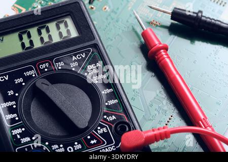 Digital Multimeter Dial and Red Probe on Circuit Board. Concept of electronic repair and diagnostic Stock Photo