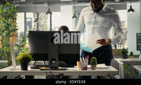 Business people using computers in workspace and analyzing projections with monthly reports. Team focuses on business intel, insights and targets under executive management. Stock Photo