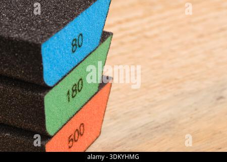 Macro shot three multi colored grinding sponges 80, 180, 500 grit stacked on light background. Focus on texture abrasive Stock Photo