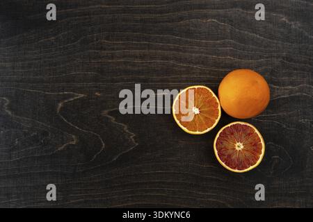 A closeup photo of vibrant organic blood oranges on a dark background with copy space Stock Photo