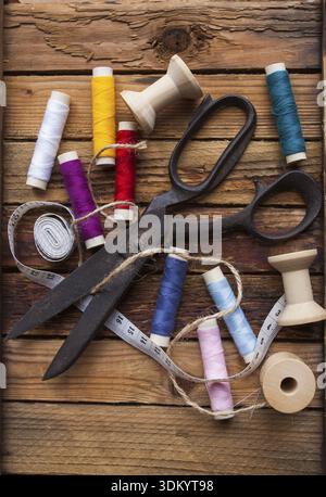 Vintage Background with sewing tools/Sewing kit. Scissors, bobbins with thread on the old wooden background Stock Photo