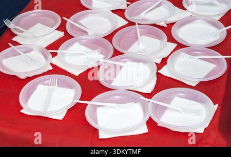 White disposable plates with forks on the red table Stock Photo