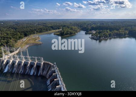 Late afternoon sun shines through clouds onto Lake Wylie flowing over dam in Catawba River Stock Photo