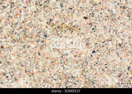 Abstract background blur - closeup of water moving over small pebbles in shallow water creating many circular patterns Stock Photo