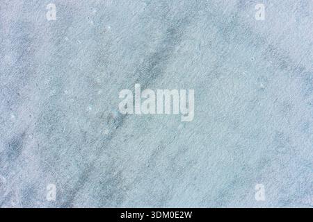Uniform surface of frozen water or packed snow with a fine grainy texture. Neutral light blue background for design and text overlays. Stock Photo