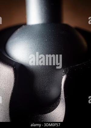 Extreme macro close-up of a matte black professional tripod ball head mount, showcasing smooth mechanical curves and fine metallic texture. Stock Photo