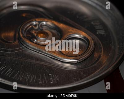 Macro close-up of a silver aluminum soda can top with a pull-tab lid, featuring warm lighting reflections and detailed metallic texture. Stock Photo
