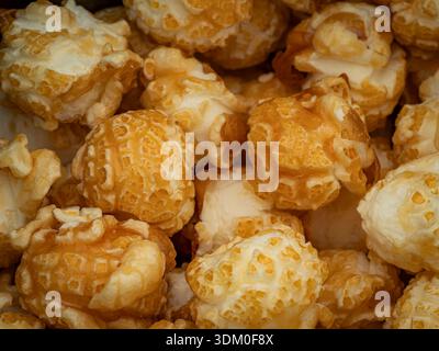 Macro close-up of gourmet caramel-coated popcorn, showcasing golden glaze and crunchy texture in a dense pile. Stock Photo