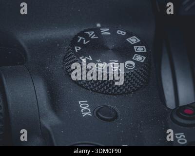 Macro close-up of a digital SLR camera mode dial featuring manual, automatic, and custom setting icons on a textured black body. Stock Photo