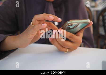 Person uses a smartphone while sitting at a table Stock Photo