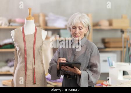 Woman dressmaker makes pattern using tablet Stock Photo