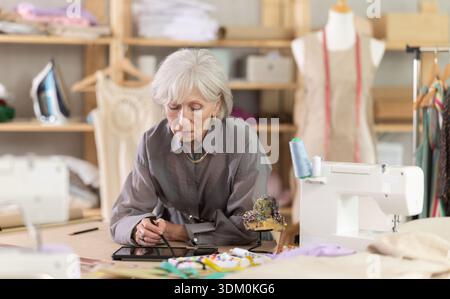 Woman dressmaker makes pattern using tablet Stock Photo