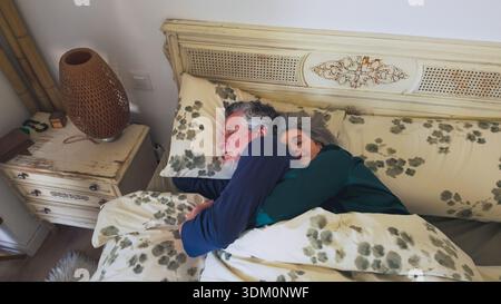 Senior couple sleeping together in bed hugging Stock Photo