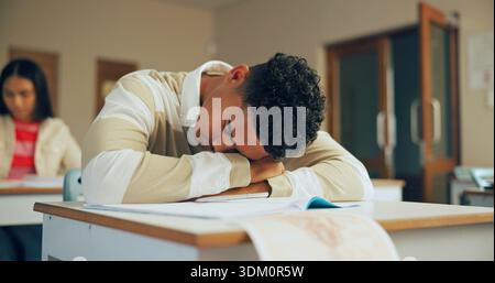 Sleeping, education and student in classroom with test, exam or assignment with fatigue or burnout. Tired, learning and boy teenager in lesson with Stock Photo