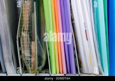 A stack of colorful files and documents on a shelf in an office Stock Photo