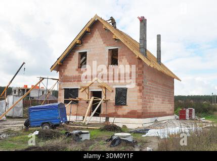 Roofer on the Roof and Lay  Asphalt Roofing Shingles. Roofing Construction House. Building House Construction Site. Building Brick House Site Exterior Stock Photo